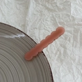 Detail of soft peach wavy hair clip with matte texture on grey ceramic plate - Pink