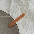Detail view of salmon pink wavy hair clip with France Handmade text on ceramic tray - Orange