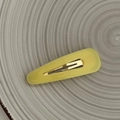 Close-up of yellow teardrop BB hair clip with matte texture on a ceramic plate - Yellow