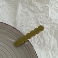 Detailed macro view of dark green wavy resin hair clip with embossed France lettering - Green
