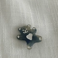 Détail macro d'un accessoire ours gris translucide avec coeur blanc sur fond texturé - Pince à Cheveux Bleu Transparent