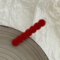 Detail view of red wavy resin hair clip with France Handmade engraved text on grey ceramic - Red
