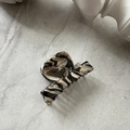 Detailed macro view of the marble texture and curved teeth on this elegant hair claw clip - Milk Coffee