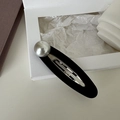 Dettaglio di un fermaglio per capelli ovale nero opaco con una grande perla grigia - Stile Perla Semplice