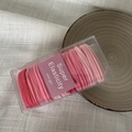 Detail of pink gradient hair ties set in a clear box on light linen fabric - Pink