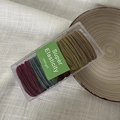 Detailed macro view of 10-piece elastic hair bands stored in a clear plastic organizer box - Deep Morandi