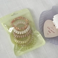 Colorful spiral hair ties set in frosted packaging on a white textured background - Yellow