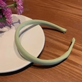 Cerchietto in tessuto verde chiaro con design imbottito su un piatto di ceramica - Verde Tinta Unita