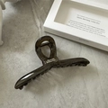 Macro detail of dark brown translucent hair claw clip with white logo on marble stone - Black and Gray