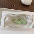 Detalle de pinzas para el cabello de resina con forma de pata de gato en una caja - Verde