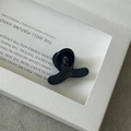 Détail macro d'une petite pince à cheveux noire sur un plateau de présentation minimaliste - Bleu foncé