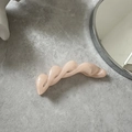 Detail of twisted banana hair clip in pearlescent peach on a minimalist grey background - Champagne