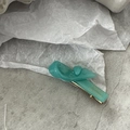 Détail de la pince à cheveux en résine bleu sarcelle avec ressort doré et texte France Handmade - Vert