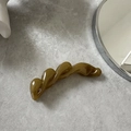 Close-up of translucent green resin banana clip with elegant wavy twist design for hair - Green