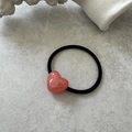Detailed close-up of a pink heart hair tie with golden lettering on a stone background - Watermelon Red