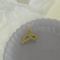 Gros plan d'une pince à cheveux dorée mate en forme de nœud sur un plateau lavande - Jaune