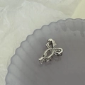 Détail macro d'une mini pince à cheveux en métal argenté en forme de nœud sur un plateau - Argent
