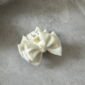 Dettaglio della piccola pinza per capelli a fiocco in raso crema con trama opaca - Bianco