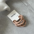 Detailed macro view of soft nude pink elastic hair bands on white card packaging - Pink