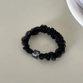 Detail of a black organza scrunchie with a translucent grey square bead accessory - Black