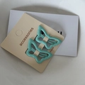 Detail of mint green butterfly hair clips on a cream card with a sleek alloy drip oil finish - Cyan