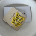 Detailed macro view of two bright yellow butterfly hair clips on a beige product card - Dark Yellow