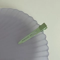 Close-up of mint green matte hollow metal hair clip on a purple textured shell tray - Green