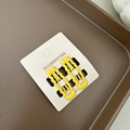 Détail de deux pinces à cheveux ondulées jaune vif sur une carte de présentation blanche - Jaune