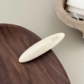 Détail de la barrette en acétate crème avec logo Barrette la France sur plateau bois - Blanc Cassé