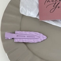 Detail of lavender purple metal duckbill hair clip with textured wavy finish on a tray - Purple
