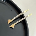 Detail of gold lucky triangle hair pins with rhinestones on a black plate surface - Triangle Rhinestone Clip / Gold