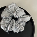 Détail d'un chouchou métallique argenté avec texture plissée sur un plateau de présentation - Chouchou Argent Métallisé