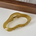 Dettaglio della molletta per capelli in resina ambrata con design a onde irregolari - Verde