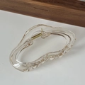 Detail view of large amber acrylic hair claw clip with irregular wavy design and metal spring - Transparent Champagne