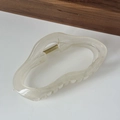 Dettaglio di grande molletta per capelli in resina bianco crema con texture marmorea - Bianco