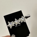 Dettaglio macro di tre fermagli per capelli a stella d'argento con cristalli bianchi - Stile Multi-Stella Bianco