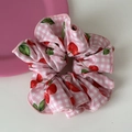 Dettaglio di elastico rosa a scacchi con stampe di ciliegie e bordo rifinito fine - Stile Ciliegia Rosa