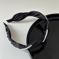 Detail eines eleganten schwarzen Satin-Haarreifens mit Perlen und Kreuzknoten-Struktur - Schwarz