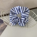 Dettaglio di un elastico a righe blu con etichetta a cuore in un cestino metallico - Bianco con Righe Blu Navy