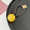 Detalle de goma para el pelo con bola amarilla translúcida y etiqueta hecha a mano - Amarillo