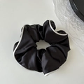 Macro detail of elegant black satin hair scrunchie with white contrast piping - Black
