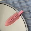 Macro detail van een matte roze haarclip op een spiegel met blauw geblokte stof - Roze