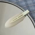 Detail shot of a cream-white matte hair clip on a mirror with a blue checkered background - White