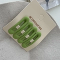 Detail von vier mattgrasgrünen Rechteck-Haarspangen auf einer weißen Produktkarte - Grün