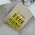 Close-up of four matte neon yellow oval hair clips on a white display accessories card - Yellow