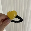 Detailed close-up of a translucent yellow jelly heart resin charm on a thick black hair tie - Yellow