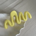 Detailed view of yellow wavy hair claw clip on white shell porcelain plate - Yellow