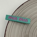 Detalle de pinza para el pelo verde con letras min min rosas en estilo moderno Y2K - Verde azulado