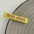 Primer plano de un pasador de pelo rectangular verde neón con letras en color rosa - Verde amarillento