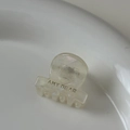 Dettaglio di una mini pinza per capelli in acetato crema con logo AMY BEAR su piatto - Bianco perla